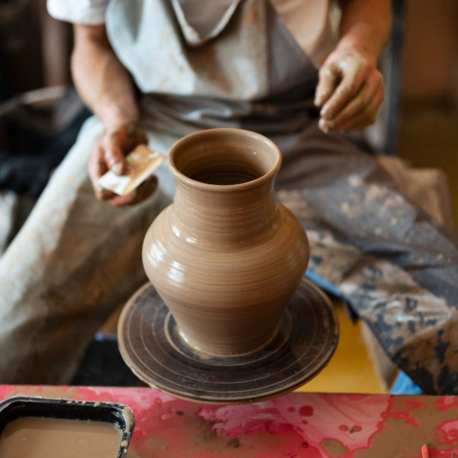 person making a vase on the pottery wheel. <a href="https://www.freepik.com/free-photo/high-angle-artisan-doing-pottery_31124470.htm#fromView=image_search_similar&page=1&position=45&uuid=613d62d3-89bd-47bb-ac75-7a9a13abf3f3">Image by freepik</a>